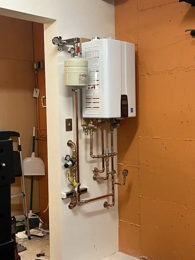 Plumbing technician inspecting water heater connections in North Codorus